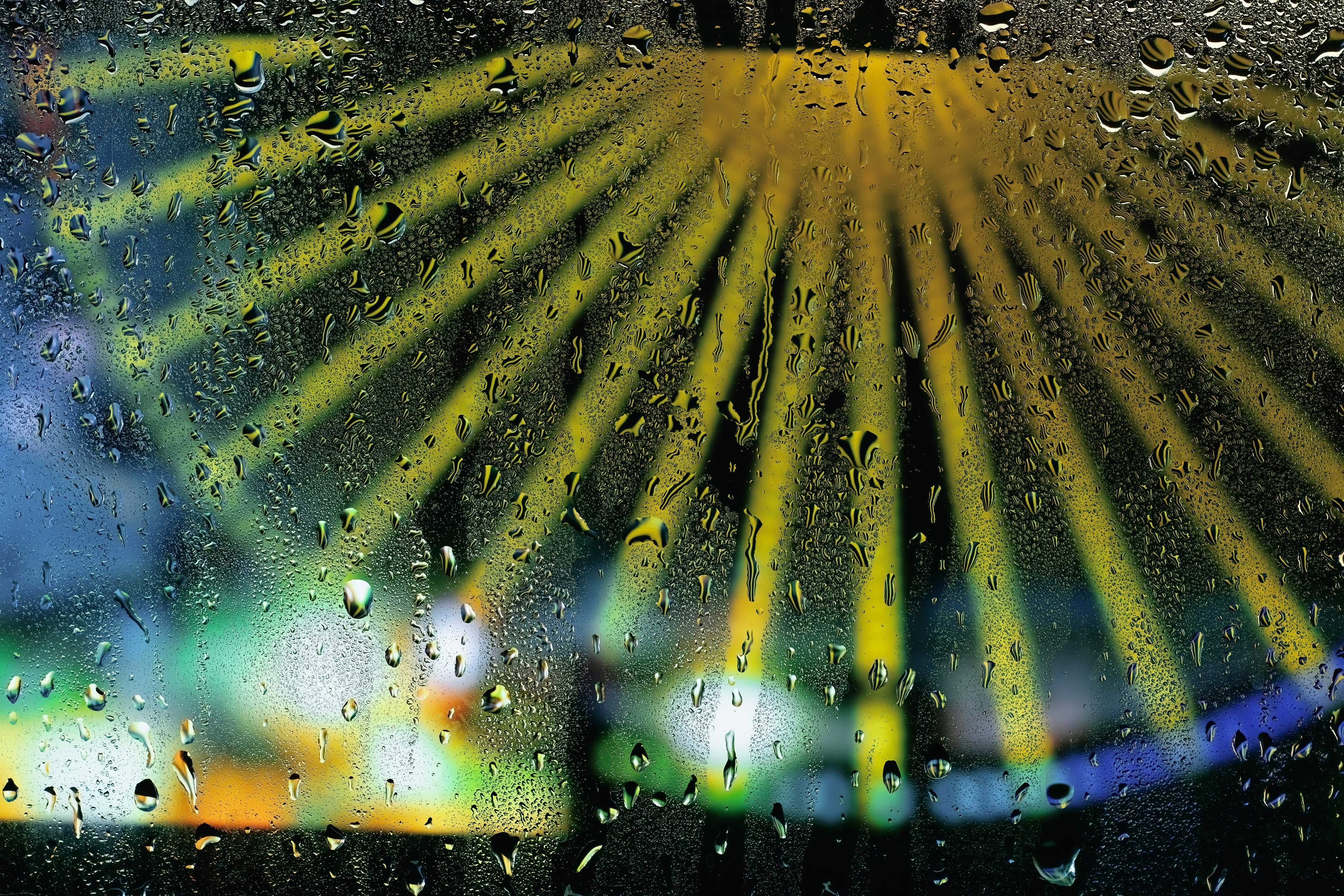 Small water droplets on a window. A bright Ferris wheel is out-of-focus on the other side of the window.